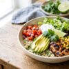 Healthy copycat Chipotle burrito bowl with chipotle chicken, cilantro lime brown rice, black beans, roasted corn salsa and avocado