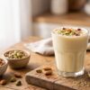 Creamy Shardai drink topped with pistachios, almonds, saffron and rose petals surrounded by traditional spices and nuts